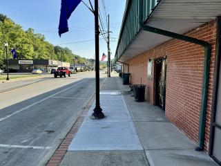 New sidewalk with bench and trashcan.