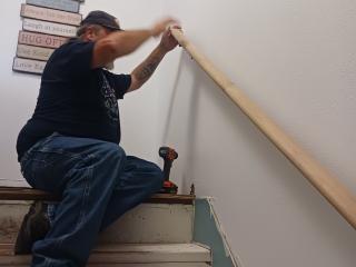 Volunteer installing new interior stair handrail.