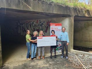 Large check presentation at tunnel entrance.