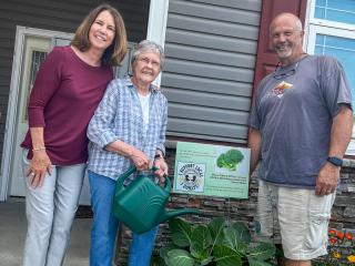 Older adult watering the vegetable in her pot.