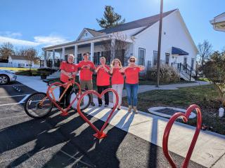 Adults making shape of a heart with their hands next to heart shaped bike racks.