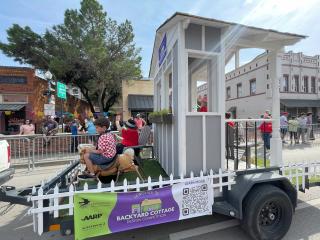 Trailer with a backyard cottage in a parade.