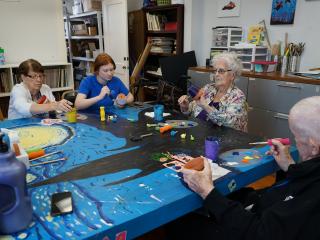 Older adults painting flower pots.