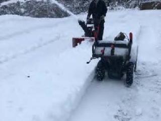 Volunteer clearing snow with snowblower.