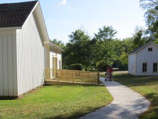 Person in wheelchair using sidewalk, adjacent to a new ramp to a historic building.