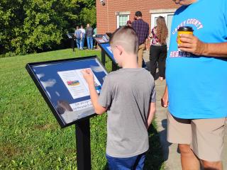 Older adult and child reading story on Storywalk panel.