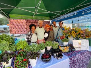 Group of farmers with table at farmers market.