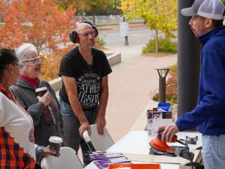 Older adults learning to use a power sander.