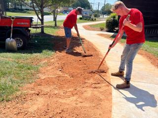 Volunteers landscaping next to new sidewalk.