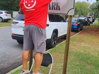 Volunteers cleaning up neighborhood sign.