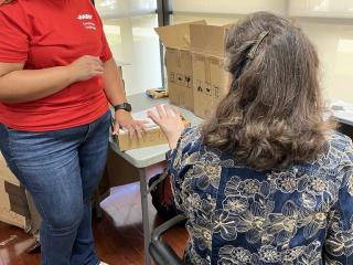 Older adult receiving help with a laptop.